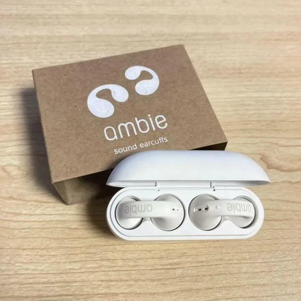 White earbud case with 'ambie' branding on a wooden surface