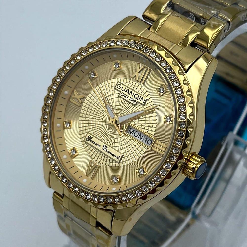 Gold wristwatch with diamond-studded bezel on a light blue background
