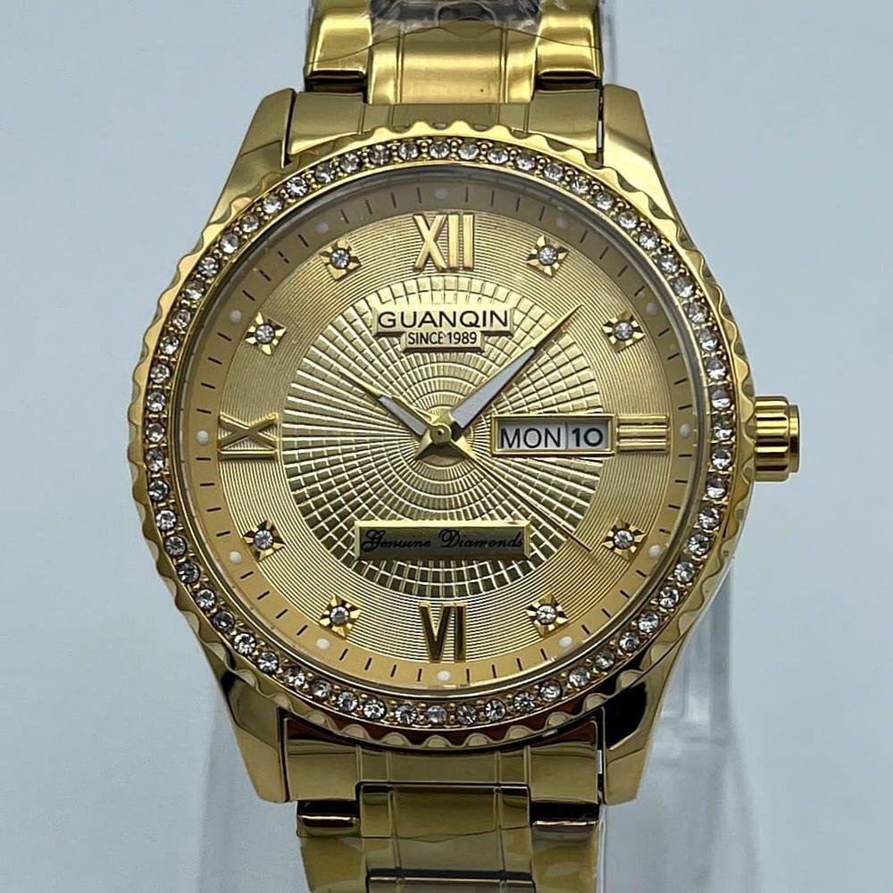 Gold watch with diamond-studded bezel on a light gray background