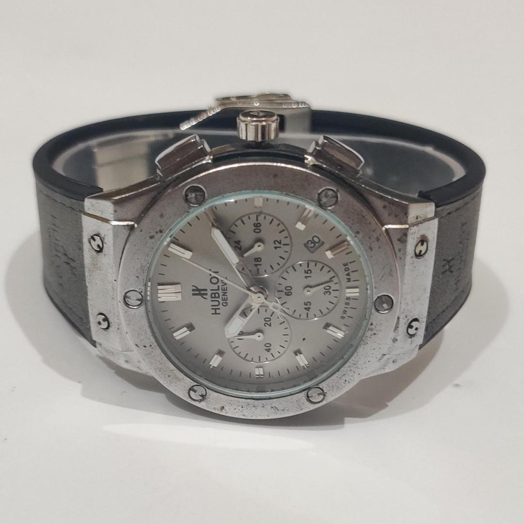Hublot watch with silver case and black strap on a white background