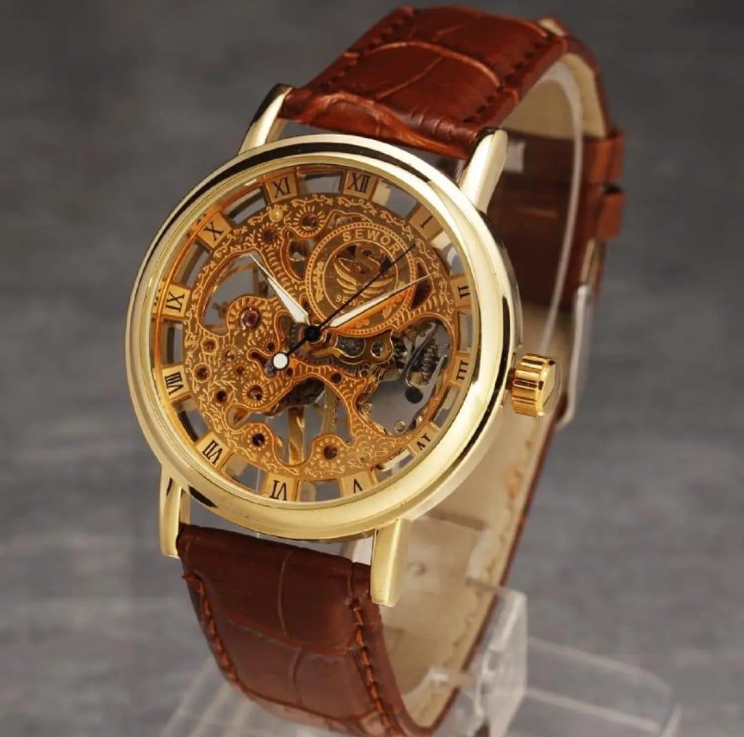 Gold mechanical watch with brown leather strap on a gray background