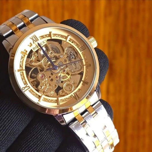 Gold and silver watch with visible mechanical components on a wooden background