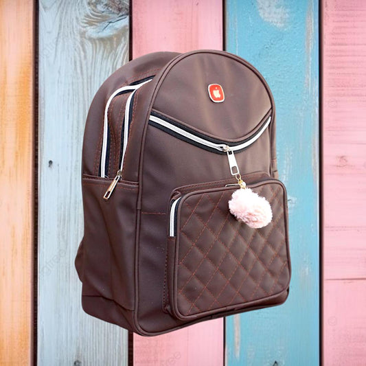 Brown backpack with a pom-pom charm on a colorful wooden background